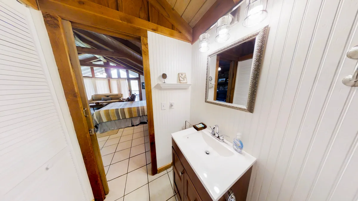 A warmly lit bathroom or vanity space, highlighting a sink and mirror set against rustic wooden beams. The inviting atmosphere evokes morning routines or winding down in the evening.