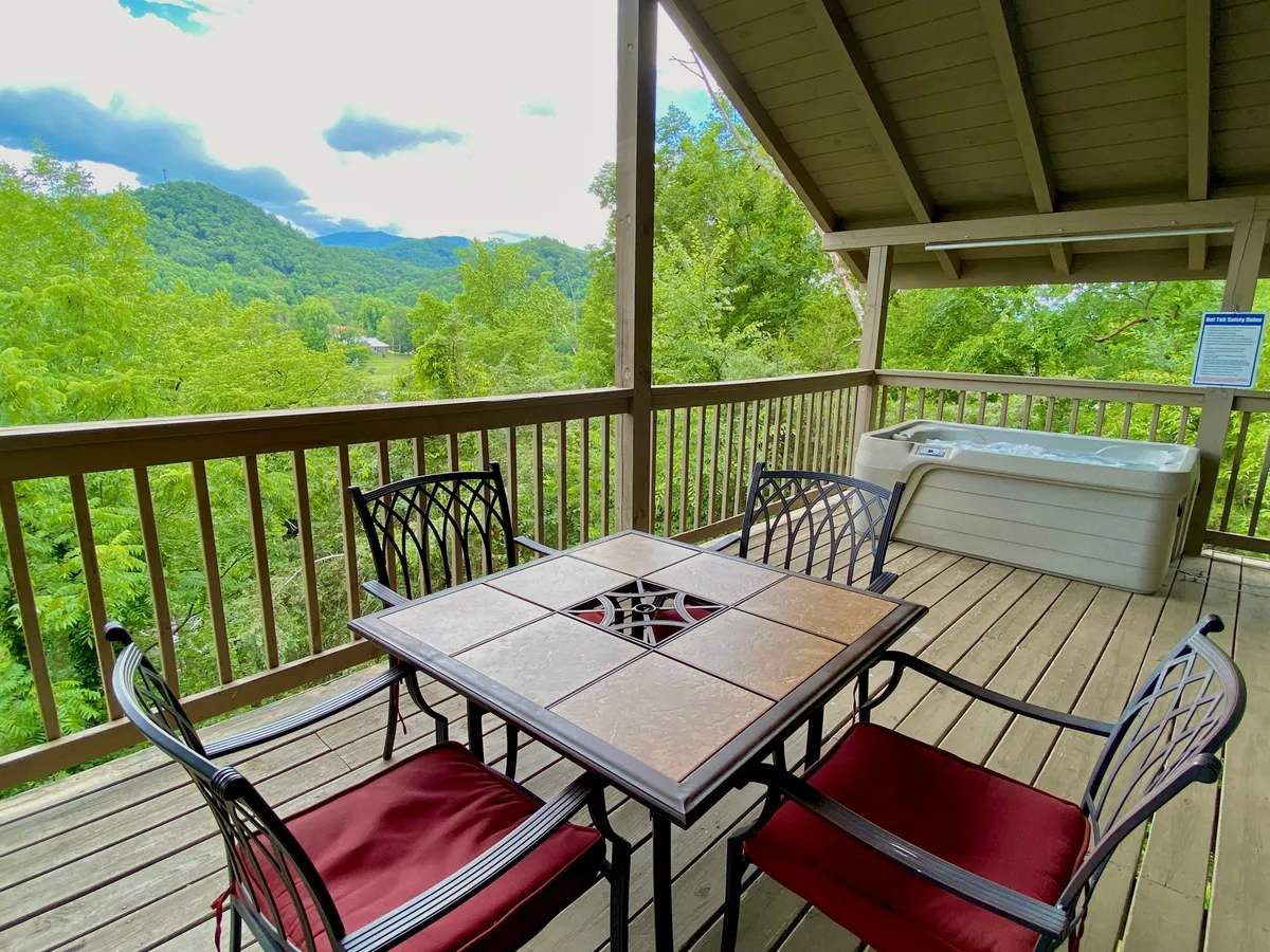 An inviting scene featuring both the dining table and hot tub with a breathtaking mountain view in the backdrop. The tranquil setting is ideal for outdoor dining, soaking in the hot tub, or simply taking in the scenery and connecting with nature.